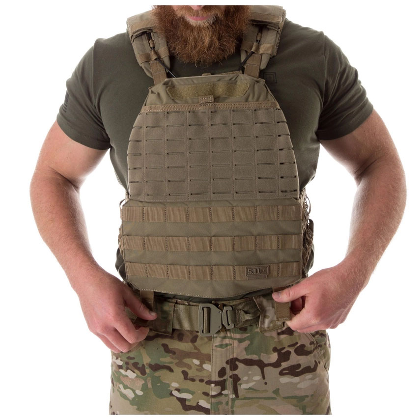 A man wearing an army vest and holding his hands in the air.