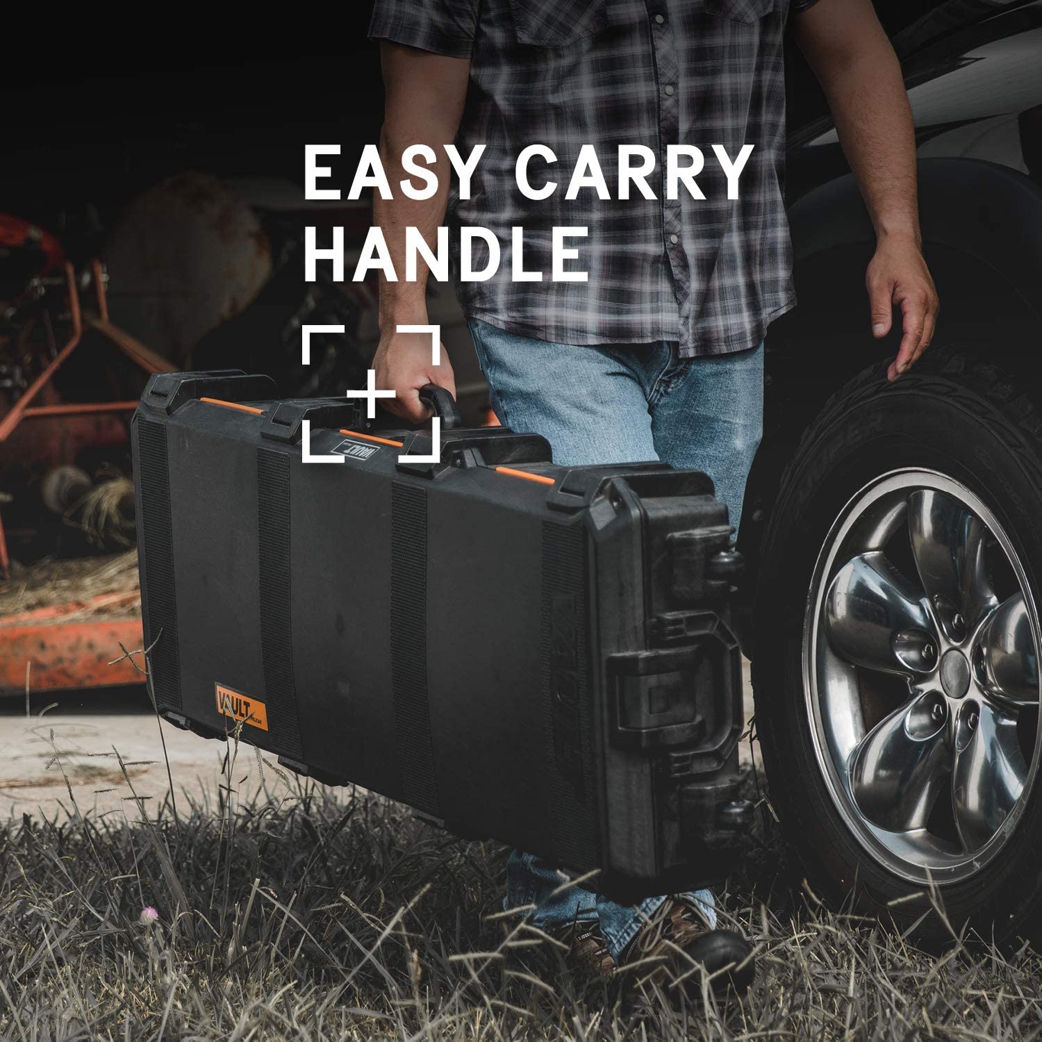 A man holding an instrument case in front of a car.