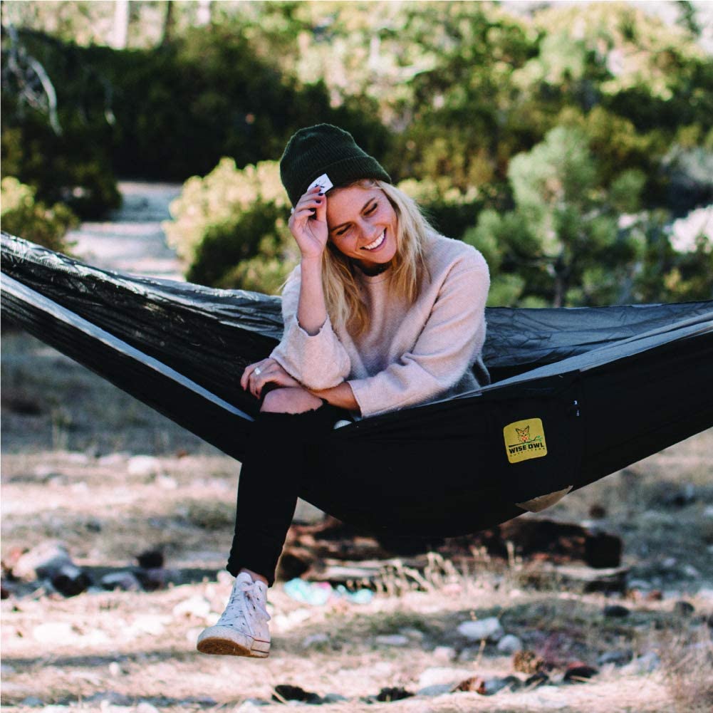 A woman sitting in a hammock on the ground.
