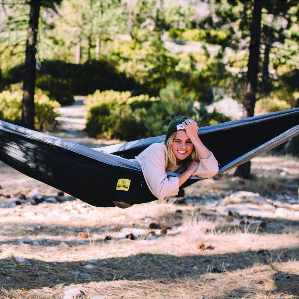 A woman laying in a hammock on the ground.