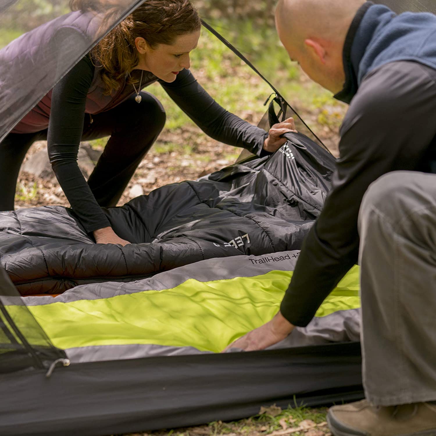 A man and woman setting up a tent.