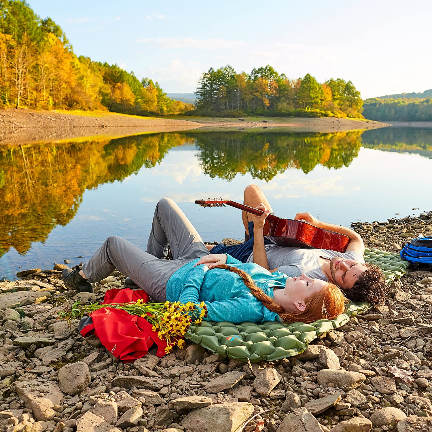 Two people laying on a blanket near the water.