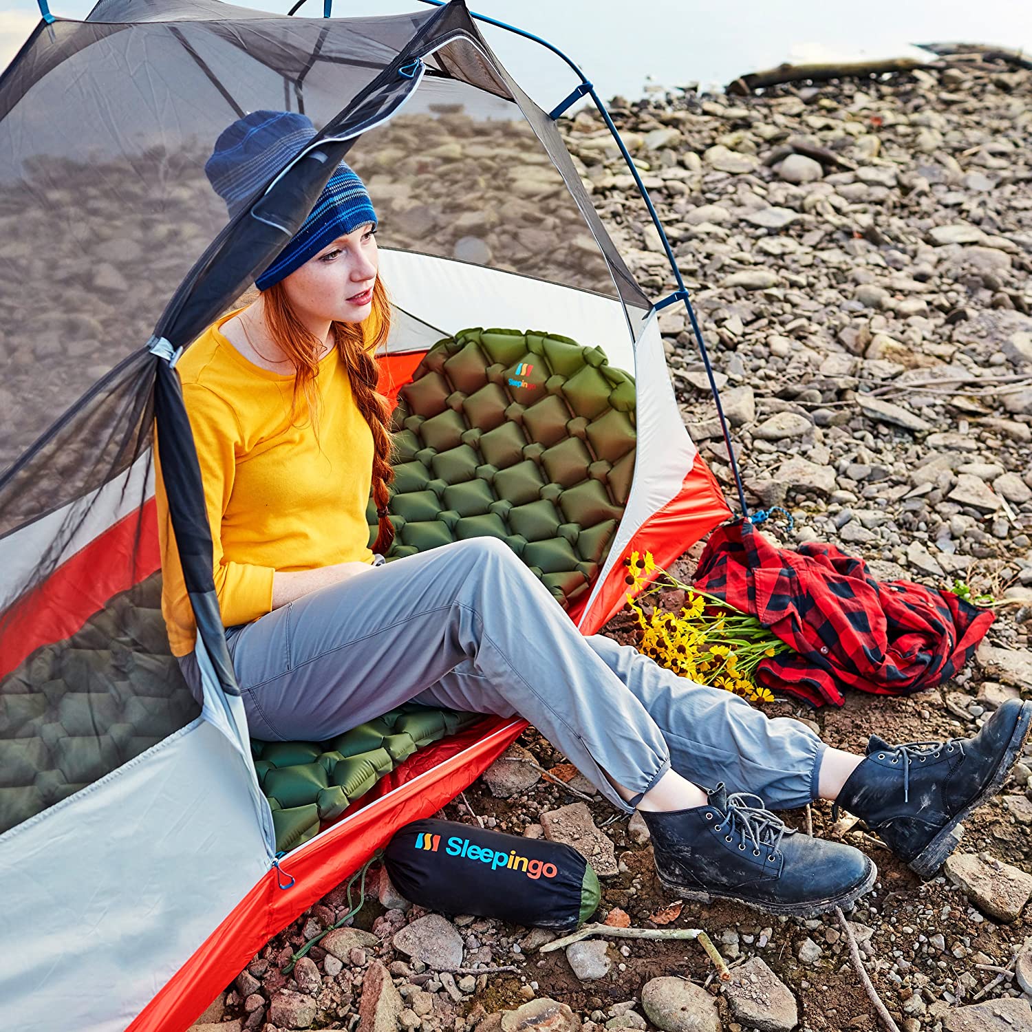A woman sitting on the ground with an umbrella.