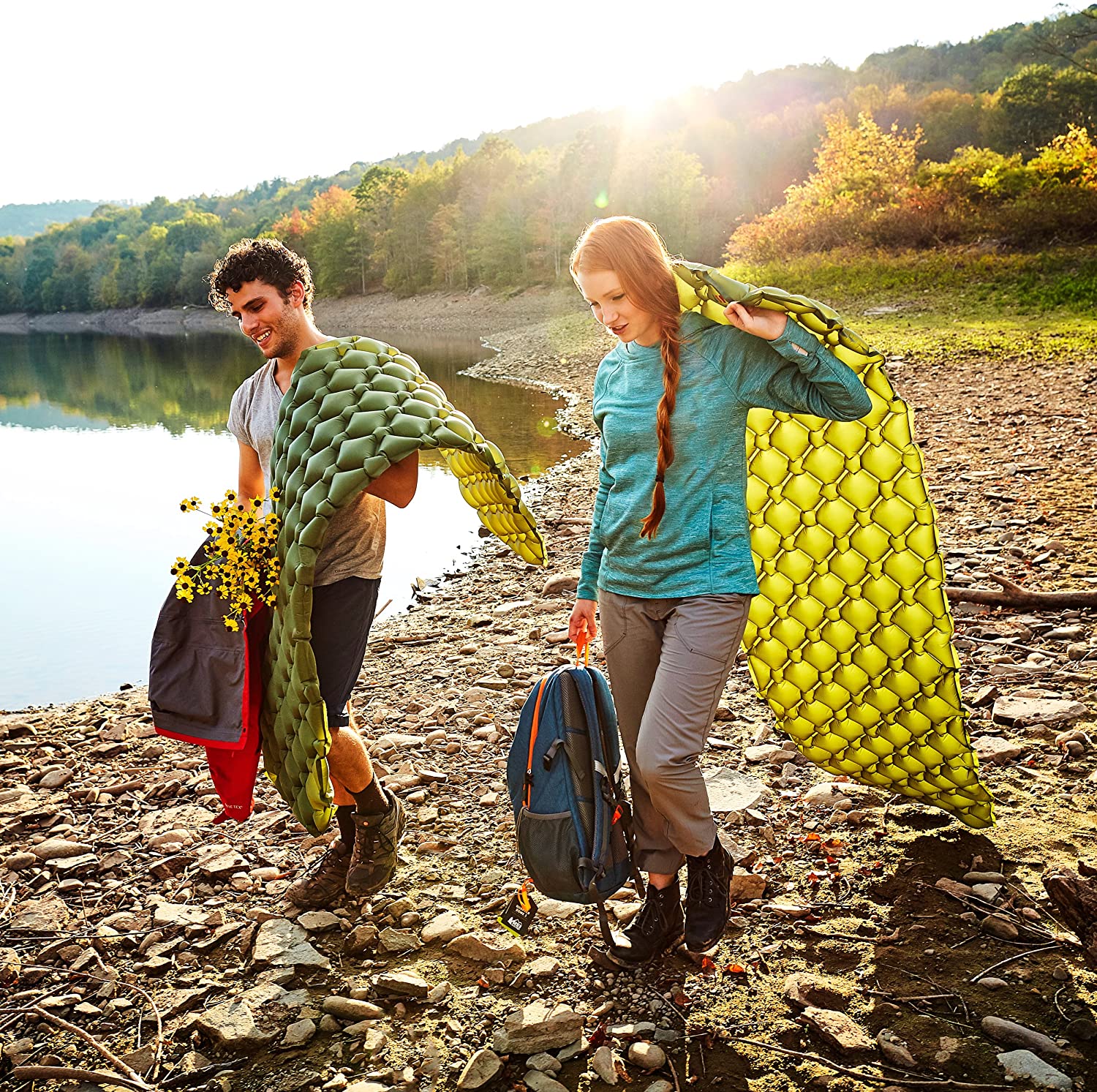 Two people walking on the beach with backpacks
